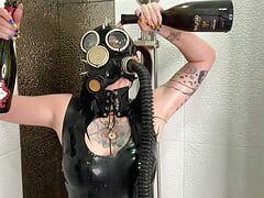 Dominatrix Nika in a gas mask pours wine over her latex body. Latex fetish